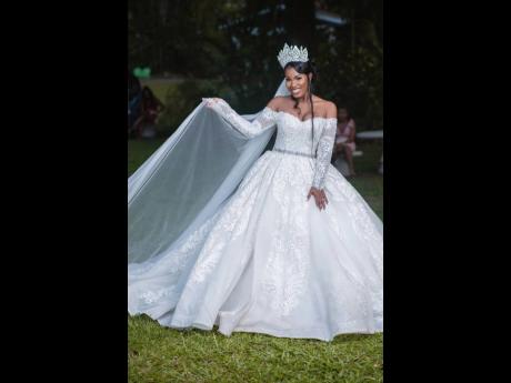 The stunning queen enchanted her groom and guests in this glamorous off-the-shoulder, long-sleeved ivory ball gown, inclusive of spectacular lace and pearl beaded details, a matching four-metre-long long and shiny, luxury lace veil and a silver zirconia cr