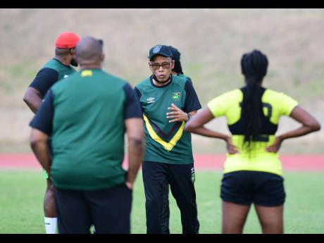 Reggae Girlz head coach Vin Blaine speaking to his charges during a training session at the Stadium East field.