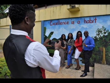 Dwayne Dubidad, principal of Stony Hill Primary and Infant, photographs some of his teachers in front of a mural he painted at the school. Dubidad has engaged in a number of beautification and development projects at Stony Hill. 