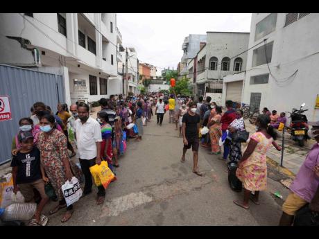 AP 
Sri Lankans queue up near a fuel station to buy kerosene in Colombo on Tuesday, April 12. The fallout from rising interest rates in the United States can be felt beyond America’s borders.