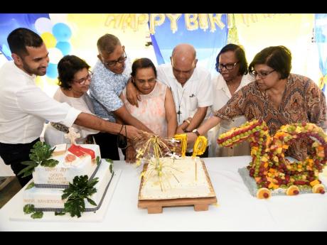 It was a family affair as Monsignor Gregory Ramkissoon, (third right) cuts his birthday cake with (from left) his nephew Siddel Ramkissoon, sister Shareeza Ramkissoon, brother Anand Ramkissoon, and sisters Carol Sammy, Roma Adam and Karen Mohammed.
