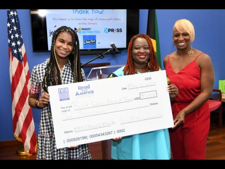 Dr Janice Johnson Dias (right), president of the GrassROOTS Community Foundation, and her daughter, Marley Dias, present a cheque to Latoya West-Blackwood, director of the Book Industry Association of Jamaica, at the US Embassy on Thursday.
