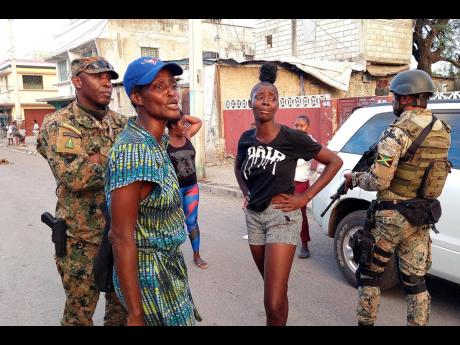 With tears welling, these women are detained after alleging abuse by soldiers in Denham Town, west Kingston, Thursday. A pregnant woman was allegedly assaulted.