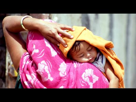 
A mother covers her child’s head with a cloth to protect from the sun on a hot and sunny day.