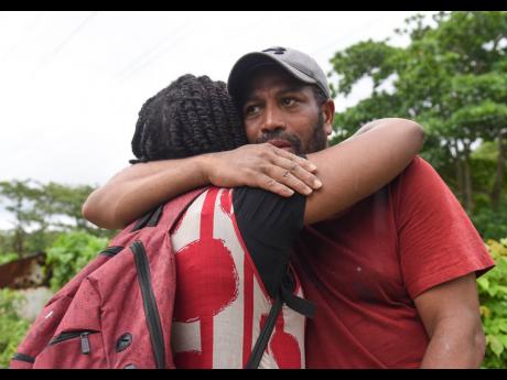 
Carl Poyser hugs his wife as she broke down in tears during their search for his mother Beryl Walters in the Montego River on Saturday, April 23. 