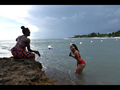 Nigerian Tesin Mai and her best friend Lee-Ann Williams enjoy the water at Treasure Beach in St Elizabeth on Thursday during their mini-vacation to the island.