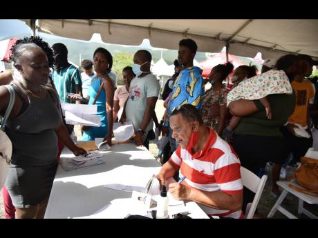 Justice of the Peace Michael Deslandes signs documents during a social services health fair held at the Donald Quarrie High School.
