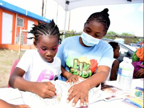 Vanessa Williams, a teacher at Donald Quarrie High School, assists Alexia Duffus with painting.