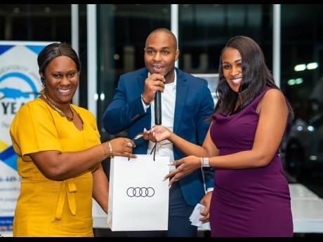  Uche Mclean (centre), sales manager, Audi Jamaica, and Channa Kay Walker, sales executive (right), issue a token from Audi Jamaica to a winning entrepreneur. 