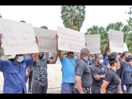 Disgruntled staff of the National Housing Trust (NHT) staging a protest at the at the intersection of Knutsford Boulevard and Oxford Road in New Kingston yesterday.