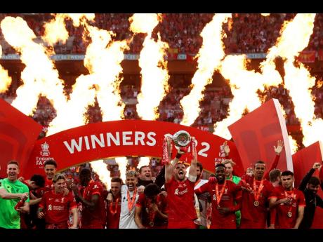 Liverpool's Jordan Henderson lifts the trophy after wining the English FA Cup final soccer match between Chelsea and Liverpool, at Wembley stadium, in London, on Saturday.
