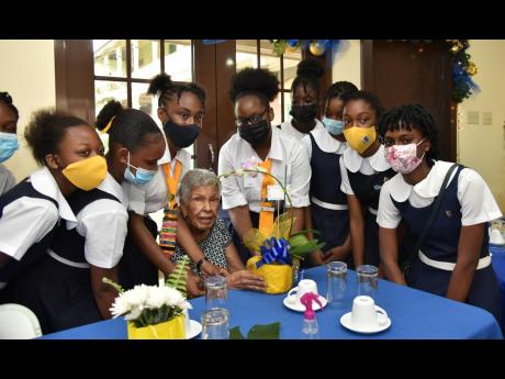 Convent of Mercy (Alpha) students (from left) Zia Gooden, Chelsea Grant, Rayan Greenwood, Shaunna-Kay Ferguson, Shari Oliver, Decon Josephs, Tevoniel Roache, Twanya-Lee Henry and Amy-Mary Fraser present an orchid to Carmen Elaine Robertson Brown, who is ce