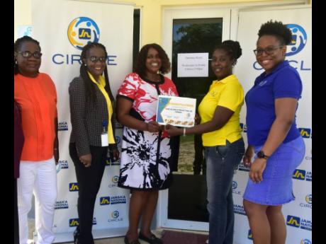 Dawnette Pryce-Thompson (second right), project coordinator at the JN Foundation presents Donna Burton (third right), centre manager at the Women’s Crisis Centre with a funding approval to outfit the new centre with furniture. Sharing in the moment are: 