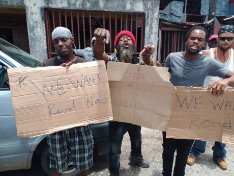Placard-bearing residents protest deplorable road conditions in the Westmoreland Central and Eastern constituencies on Monday.