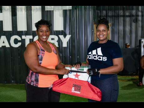 Red Stripe Brand and Corporate PR Manager, Stacy-Ann Williams-Smith (left) shares in Cheers to a Dry Lent Challenge third-place winner Samantha Brown’s joy as she collects her prize following an intense 40-day focus on wellness.