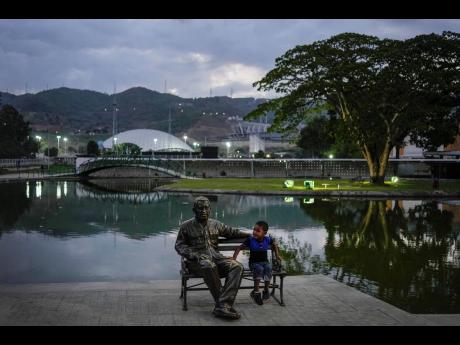 A child sits next to a monument of late President Hugo Chavez at Hugo Chavez Park in Caracas, Venezuela, on May 14. The United States government is considering lifting some economic sanctions on Venezuela.
