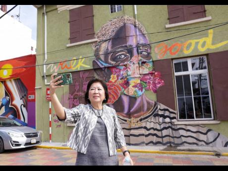 Mari Pangestu takes a selfie in front of mural in downtown Kingston.
