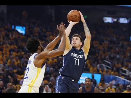 
Dallas Mavericks guard Luka Doncic (77) shoots against Golden State Warriors forward Andrew Wiggins during the first half of Game Two of the NBA basketball playoffs Western Conference finals in San Francisco on Friday, May 20.