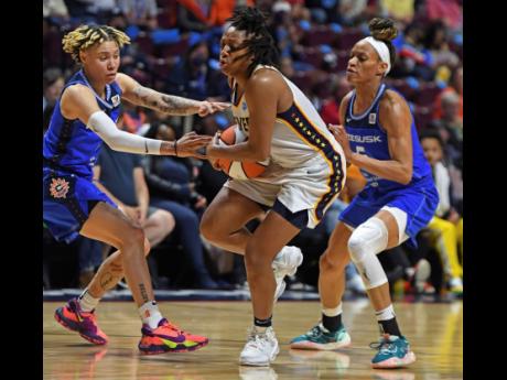 
Indiana Fever guard Kelsey Mitchell (centre) drives between Connecticut Sun guards Natisha Hiedeman (left) and Jasmine Thomas during a WNBA basketball game on Friday.