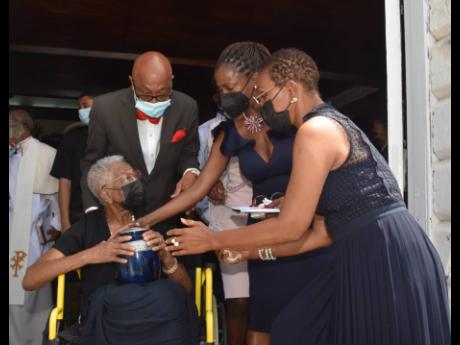 Laura Donaldson holds the urn with the ashes of her late husband, Cecil Donaldson. Assisting her is Fitzroy Donaldson (nephew), Marsha-Ann Donaldson (daughter) and Donna Donaldson (niece), as they depart the thanksgiving service for the life of the former 