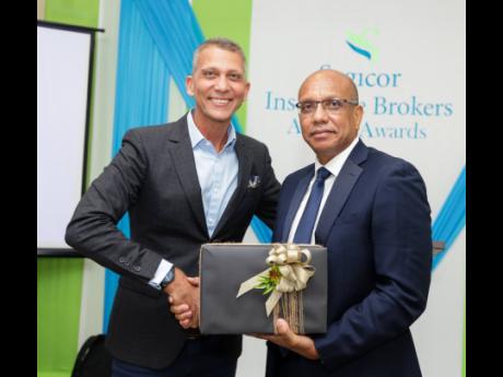 Peter Melhado (left), chairman of Sagicor Group Jamaica Limited, receives a gift of appreciation from Dave Hill, general manager of Sagicor Insurance Brokers.
