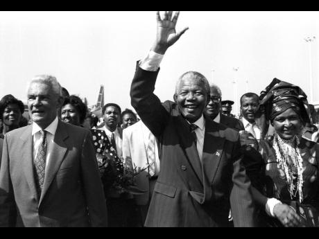 Nelson Mandela is flanked by his wife Winnie and then Prime Minister Michael Manley during a visit to Jamaica in 1991.