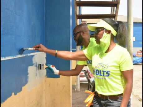 Jullite Reeves (foreground), admin assistant at the Jamaica Public Service Company, and Allaine Harvey, programmes officer at the JPS Foundation, painting sections of the police post at the Charles Gordon Market on Labour Day.