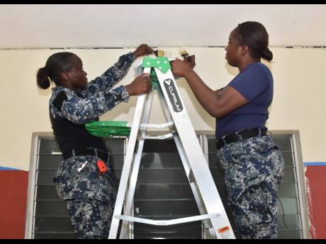 Kerry-Ann Collins (left) and Shanece Landle, ordinary seaman, painting sections of the hallway at the Caribbean Christian Centre for the Deaf in Granville, St James, as part of the NCB Foundation’s Labour Day project on Monday, May 23.