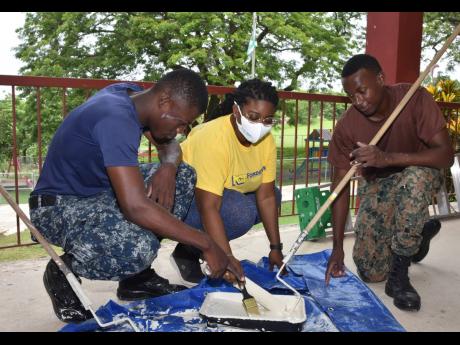 From left: Samuel Rowe (ORD), Latara Boodie (NCB) and Rajay Sterling (ORD) mix paint during NCB Foundation Labour Day project at the Caribbean Christian Centre for the Deaf in Granville, St James, on Monday.  