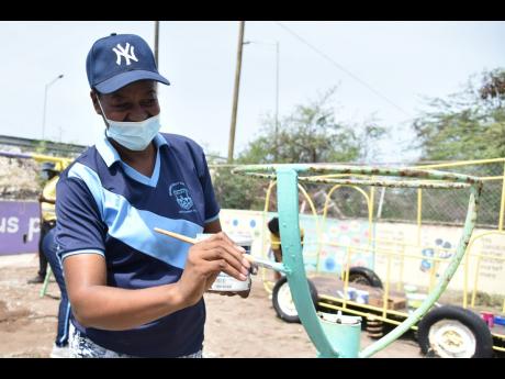 Clover Johnson, principal of the Seaview Early Childhood Development Centre,located in Harbour View, St Andrew, paints a metal hoop at the school’s playground  on Monday. The China Habour Engineering Company undertook a Labour Day project at the school t