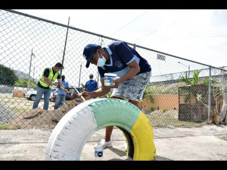 Clover Johnson, principal of the Seaview Early Childhood Development Centre,  located in Harbour View, St Andrew, paints a tyre at the school's playground  on Monday. The China Habour Engineering Company carried out its Labour Day project at the school to 