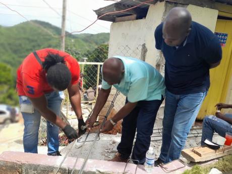 Mayor of St Ann’s Bay Sydney Stewart (centre) assists Kamani Wallace  of the St Ann Municipal Corporation’s technical department, while Member of Paarliament Zavia Mayne looks on, during Labour Day work at Grants Bailey Basic School on Monday.