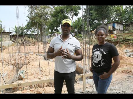 Dwight Sibblies, member of parliament for Clarendon Northern explains to Jordeen Mason the support being provided during the construction of a two bedroom house for her mother Joan Douglas. 