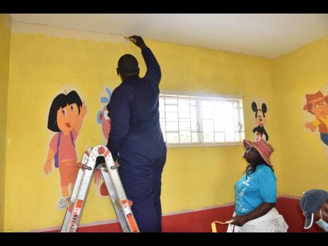 Volunteers from JEP help to make one of the classrooms at Blackwood Gardens Basic School more appealing and conducive to learning.