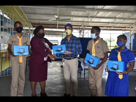 National Security Minister  Dr Horace Chang (centre) presenting tablets to students at the Glendevon Primary and Infant School. Others in the photo are (from left) Madrid Wilkins, a student, Audrey Lee-Peynado, principal of Glendevon Primary and Infant Sch