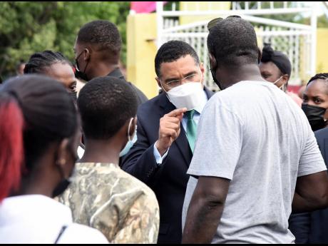Prime Minister Andrew Holness (centre), member of parliament for St Andrew West Central, speaks with residents of his constituency yesterday, shortly after the launch of a public W-Fi access point installed by the Universal Service Fund at the Seaward Prim