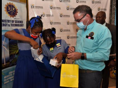 Daryl Vaz (right), minister of science, energy and technology, looks on as Oneila Mitchell (left) and Keleece Charron, students from St Patrick Primary School eagerly try to open the new phones they got from the minister. They were attending the Universal 