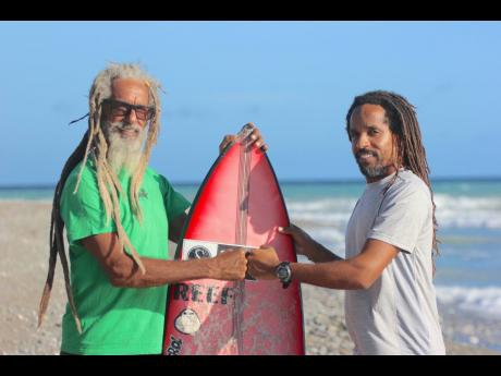 
From left: Outgoing Jamaica Surfing Association President Billy Wilmot passes on a surfboard in a symbolic gesture to new President Inilek Wilmot.