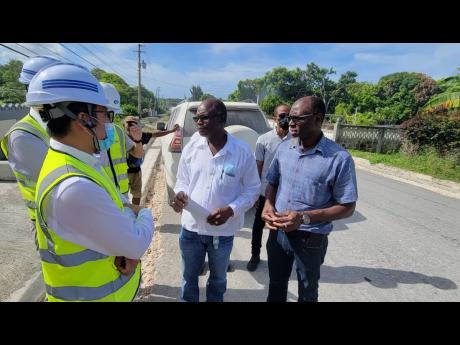 Minister with responsibility for roads, Everald Warmington (centre), and Communication Manager at National Works Agency Stephen Shaw (right)engage representatives of China Harbour Engineering Company during a tour of sections of the Southern Coastal Highwa
