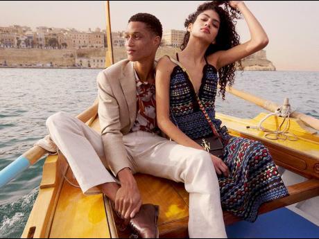 At right: Summer boating in luxe fashion, the SAINT star’s Havana print Sandro shirt and cream James Perse trousers is paired with a Corneliani blazer as he sits alongside Venezuelan model Antonella Delgado.