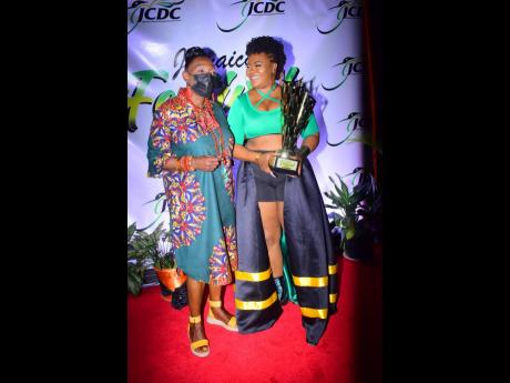 Dancehall artiste Stacious accepts the award from Entertainment Minister Olivia ‘Babsy’ Grange during the result show for the 2021 version of the National Festival Song Competition at the National Indoor Sports Centre.