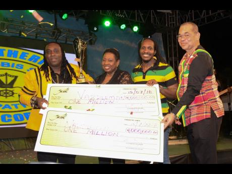 Winner of  the Jamaica Festival Song 2018 Grand Finals Nazzle Man (left) is presented with the grand prize of one million dollars by Minister of Culture, Gender, Entertainment and Sport Olivia Grange, and Interim  Executive Director of JCDC, Orville Hill.