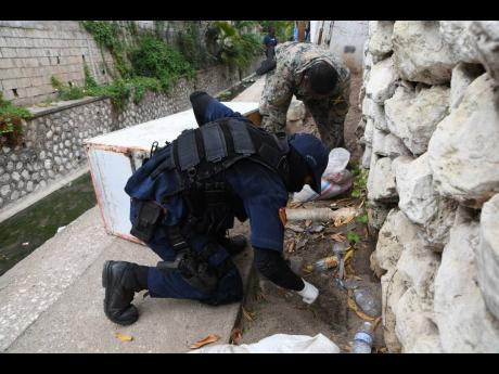 Members of a police-military team search for guns and ammunition during an operation in Grants Pen on April 4, days after a triple murder. Despite talk of relative peace in the northeast St Andrew community, guns and gunmen are still a reality there.