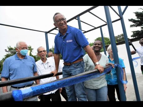 Glendon Nam, director of Island Dairies/Cremo, testing exercise bars donated by the company to the Grants Pen Peace Park in northeast St Andrew on Sunday. From left are Minister of Justice Delroy Chuck, Pastor Ian Muirhead, Joy Cotterel, councillor of the 