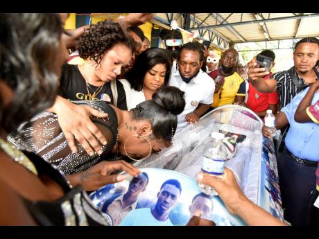Mourners crowd the coffin of the 18-year-old St Andrew Technical High School football star Omar Laing at his funeral on Wednesday. Omar was killed by gunmen in Denham Town on April 22.