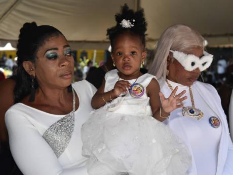 Marcia Myers holds one-year-old Omarliyah Laing, daughter of the late St Andrew Technical High footballer Omar Laing, at his funeral on the school grounds on Wednesday. 