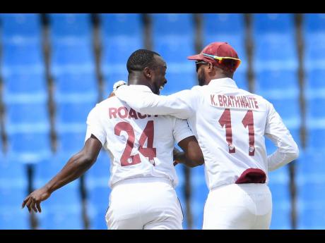Kemar Roach (left) and Kraigg Brathwaite of the West Indies celebrate the dismissal of Najmul Hossain Shanto of Bangladesh before lunch on yesterday’s opening day of the first Test between Bangladesh and West Indies at the Sir Vivian Richards Cricket Sta