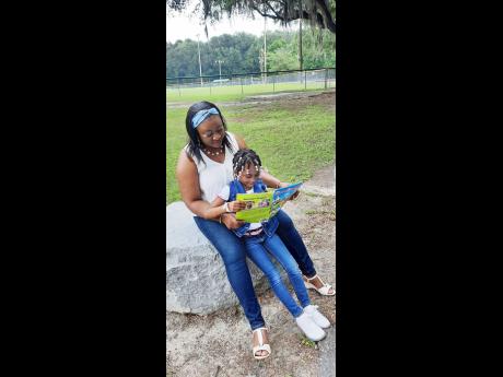 Tashana Sewell assists her daughter, Kennedy, as she reads a book.