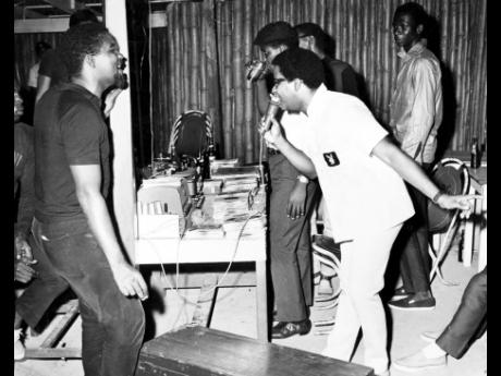 
In this 1967 picture, Winston Blake (with mic) of the Merritone Discotheque is caught in a happy mood at Club Sombrero at a Sunday session. Beside him is brother Trevor (having a drink) with fans looking on.