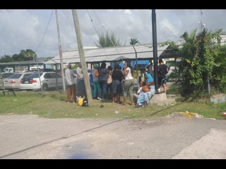 In this 2018 photo, relatives of SOE detainees wait at the fence of the Freeport Police Station in St James.  Human rights advocates estimate that over 11,000 people were detained for extended periods under the SOEs since 2018, which, at one point, was imp